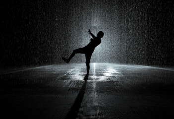 Artistic shot of silhouette of a person dancing in the rain