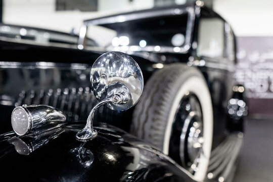 Rear view mirror of classic luxury car from 1930s in the UK (selective focus or defocused background)