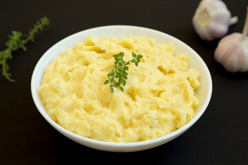 Homemade Garlic Mashed Potatoes on a black background, side view.