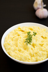 Homemade Garlic Mashed Potatoes on a black surface, side view.