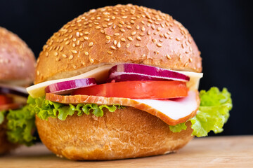 burger with meat cheese tomato onions on a board on a black background