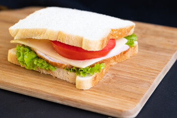 sandwich with tomato ham salad cheese on a wooden board