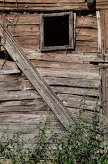 Exterior wall with a broken window of an old wooden cottage. Wooden wall of log hut
