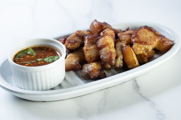 Deep fried pork belly with fish sauce and spicy sauce in white plate