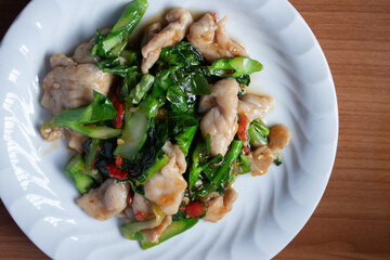 Stir-fried pork with kale and chilli in a white plate