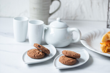 Cookies in a white plate, teapot, afternoon snack.