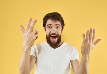 emotional man with a beard in a white t-shirt gestures with his hands
