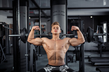 Fototapeta na wymiar Close Up of a muscular young man lifting weights in gym on dark background. High quality photo