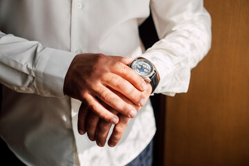 Fototapeta premium a man in a white shirt puts a watch on his hand