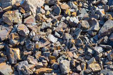 bright contrasting rocks broken by the waves of the sea a variety of shapes and textures lies on...