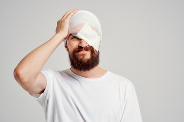 sick man with bandaged head and eye hospitalization light background