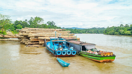 Timber loaded into big barge then drag by a tugboat cruising Mahakam River, Borneo, Indonesia