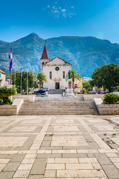Saint Marko cathedral and church at Makarska city, Croatia. The Biokovo mountains in the background. Sunny day at summer, green trees on the side. Dalmatia region.