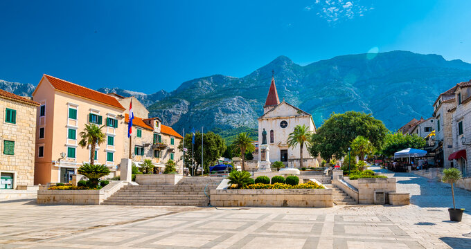Saint Marko cathedral and church at Makarska city, Croatia. The Biokovo mountains in the background. Sunny day at summer, green trees on the side. Dalmatia region.