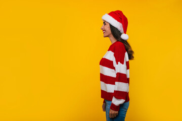 Side view photo of smiling attractive young woman in Christmas hat isolated on yellow wall