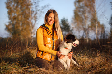 Naklejka na ściany i meble Portrait of a Girl in Yellow and Border Collie on a Nature Background