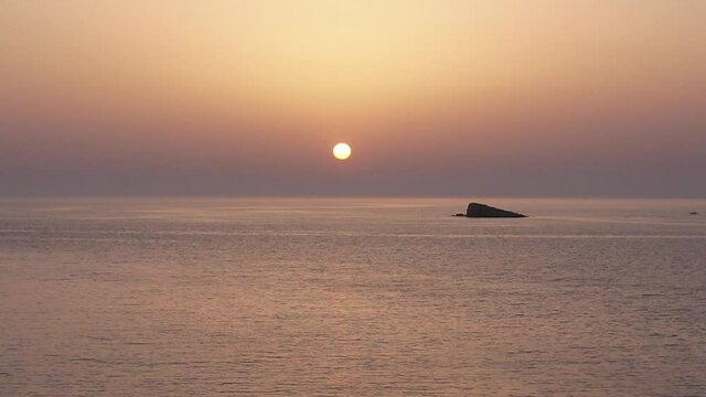Plan de drone minimaliste au dessus de la mer avec le coucher de soleil en arri&egrave;re-plan et un petit bateau qui passe