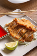Oriental style battered chicken fillet with sweet and sour sauce, vertical image.