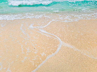 Fototapeta na wymiar Blue water, waves crashing on the shore causing air bubbles.
