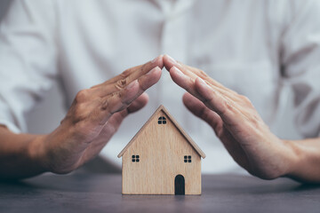 Home security concept, home insurance for real estate, protecting gesture of man and house model.