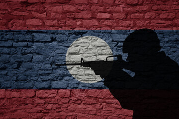 Soldier silhouette on the old brick wall with flag of laos country.