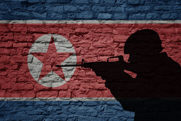 Soldier silhouette on the old brick wall with flag of north korea country.