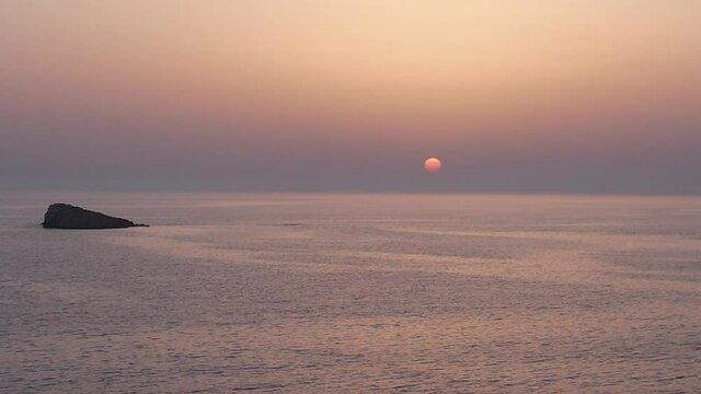 Plan de drone minimaliste au dessus de la mer avec le coucher de soleil en arri&egrave;re-plan et un petit bateau qui passe