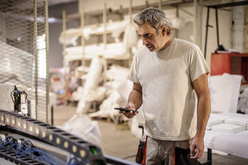 Factory worker resting and using mobile phone in workshop