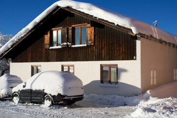 OBERSTAUFEN, GERMANY - 29 DEC, 2017: Typical wooden house in the German Alps in winter with a lot of snow on the roof and a snow-covered car in front of it