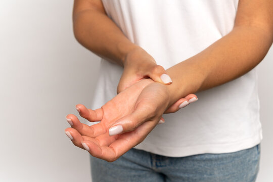 Woman holding fingers on wrist checking pulse. Tired female touching arm to measure heart beat or blood pressure, massages wrist after working at computer, pressing vein with hand. Arthritis concept.
