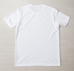 Blank white T-shirt mockup template on the floor.