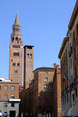 Fototapeta premium Torrazzo of Cremona. Torrazzo of Cremona and ancient palaces.A street in the center with the tall bell tower with clock, symbol of the city, made of bricks. 