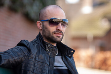 Portrait of a handsome bearded man from Poland wearing sunglasses and a leather jacket