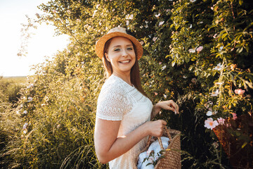 Pretty woman in hat holding basket with flowers