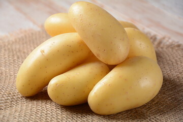 Little yellow potatoes clean ready for cooking on burlap sack as background