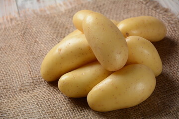 Little yellow potatoes clean ready for cooking on burlap sack as background