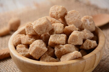 Demerara brown sugar cubes in wooden bowl. Also called sugar lumbs. Sucrose sugar product with distinctive brown color due to the presence of molasses.