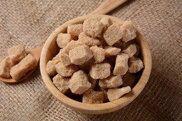 Demerara brown sugar cubes in wooden bowl. Also called sugar lumbs. Sucrose sugar product with distinctive brown color due to the presence of molasses.