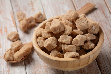 Demerara brown sugar cubes in wooden bowl. Also called sugar lumbs. Sucrose sugar product with distinctive brown color due to the presence of molasses.