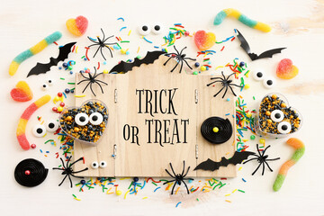 holidays image of Halloween. bats, spiders and wooden board frame with text over white table