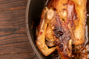 Pieces of roast duck with spices in a frying pan, close-up, selective focus.