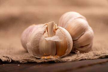 Heads of young garlic on a table covered with burlap, close-up, selective focus.