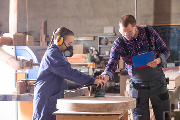 Experienced carpenter teaching young apprentice at workshop