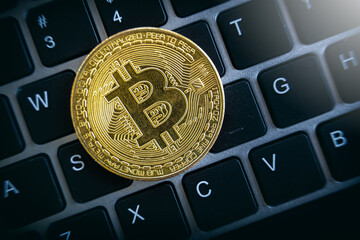 Close up of golden bitcoin on laptop keyboard. Cryptocurrency investments.