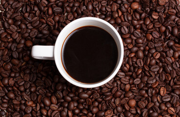 Vista de una taza de café blanco sobre un fondo de granos de café