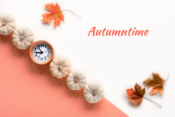 Text Autumntime, alarm clock and decorative white pumpkins. Layered off white and orange paper flat...