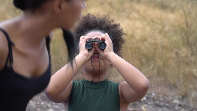 african american Girl looking through binoculars . black kid in Forest nature park