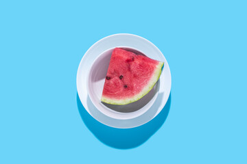 Slice of juicy red watermelon in a plate on a blue background. Top view, flat lay