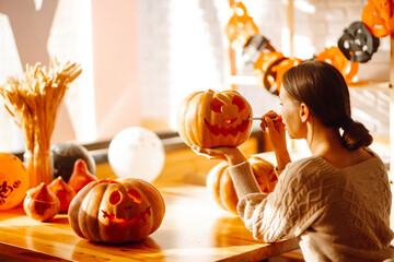 Young woman cutting with knife character face on pumpkin object preparation to halloween holiday....