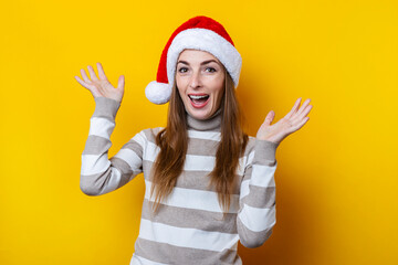 Fototapeta na wymiar Joyful young woman in Santa Claus hat on a yellow background